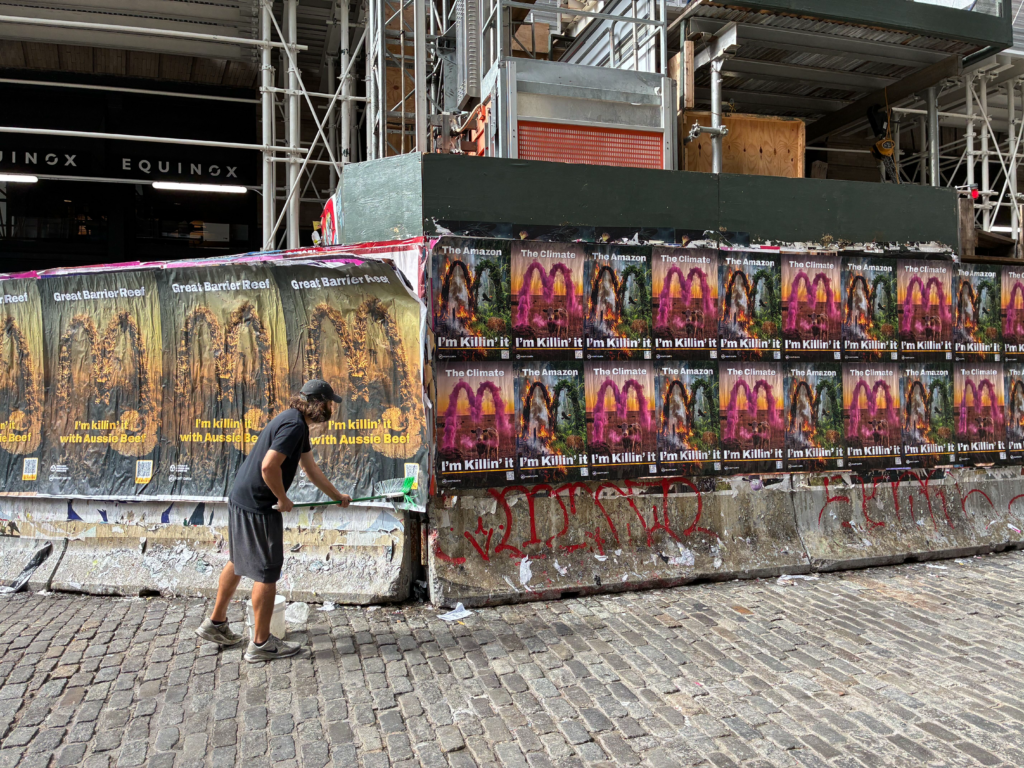 The image shows a person putting up a wheatpaste poster during a protest against McDonald's in New York.
